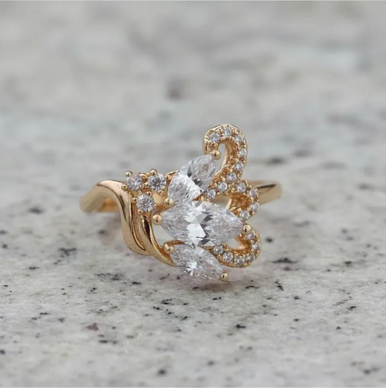 Belleza que florece con propósito  Inspirado en la suavidad de la naturaleza, este anillo dorado presenta un diseño en forma de hoja adornado con cristales tipo marquise y detalles curvos que evocan el movimiento del viento. Es una joya que transmite gracia, renovación y fortaleza interior.  Cada cristal refleja luz con elegancia, como un recordatorio de que lo natural también puede ser deslumbrante.  🔸 Material: Aleación con baño dorado 🔸 Diseño: Hoja decorativa con cristales marquise y detalles curvos con incrustaciones 🔸 Color: Dorado brillante con cristales transparentes 🔸 Inspiración bíblica: “Será como árbol plantado junto a corrientes de aguas, que da su fruto en su tiempo, y su hoja no cae…” — Salmo 1:3  Una joya para quienes encuentran fuerza en sus raíces y florecen a su tiempo.  📏 ¿Tienes dudas con la talla? Encuentra nuestra guía de tallas en el carrusel de fotos del producto.